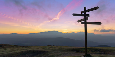 Direction Signs at Dusk with Mountains in Distance